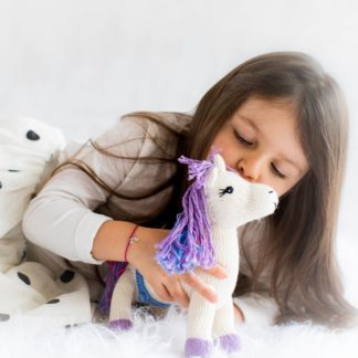 Mädchen gibt Bio Kuscheltier Einhorn einen Kuss